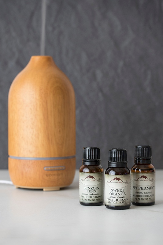 Bottles of essential oils next to a wooden diffuser