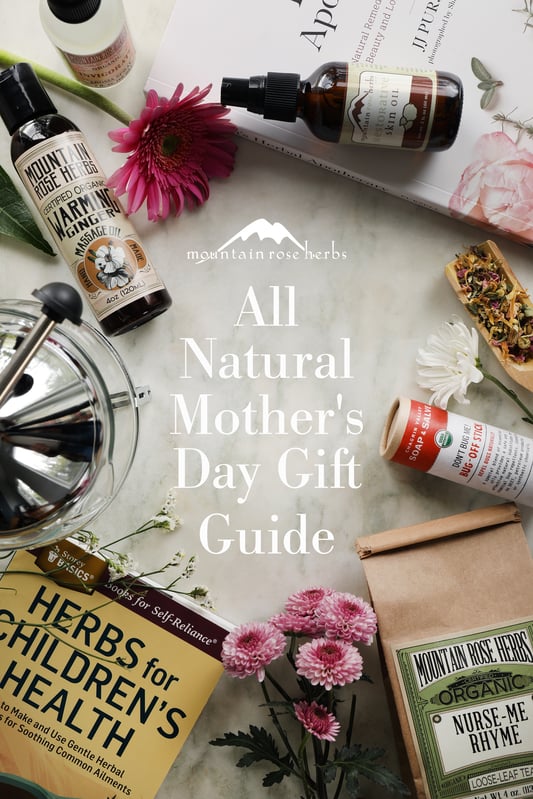 Pinterest pin for All Natural Mother's Day Gift Guide. Many mother's day gifts arranged on a marble counter top with flowers.