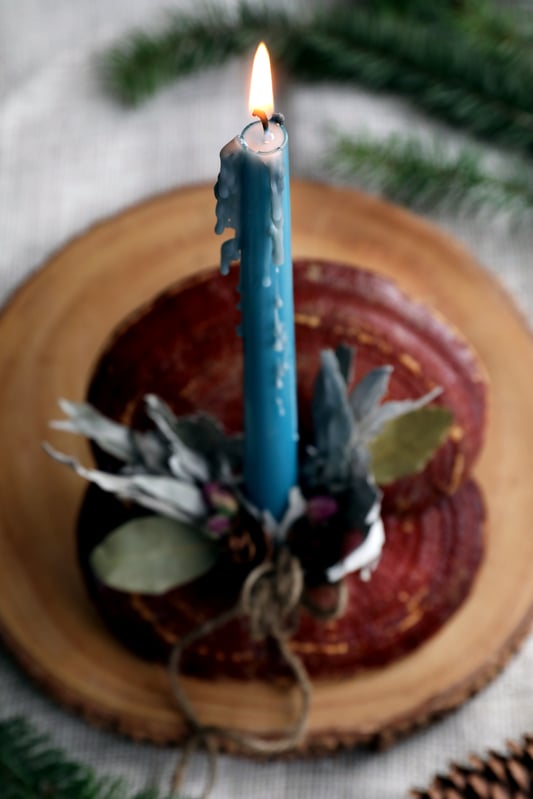 Candle burning on top of reishi mushroom centerpiece with botanical accents
