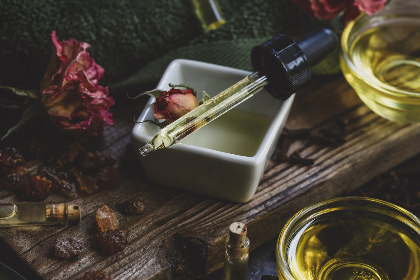 Bowls of fungus fighting nail oil with dried roses and a dropper