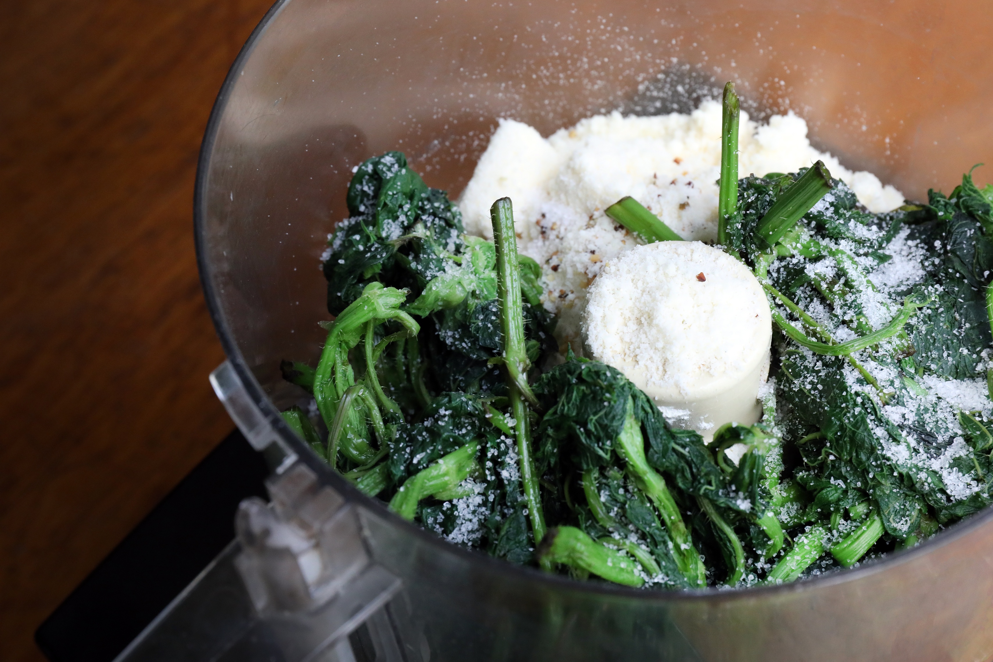 Blanched nettle leaves and other pesto ingredients in a food processor