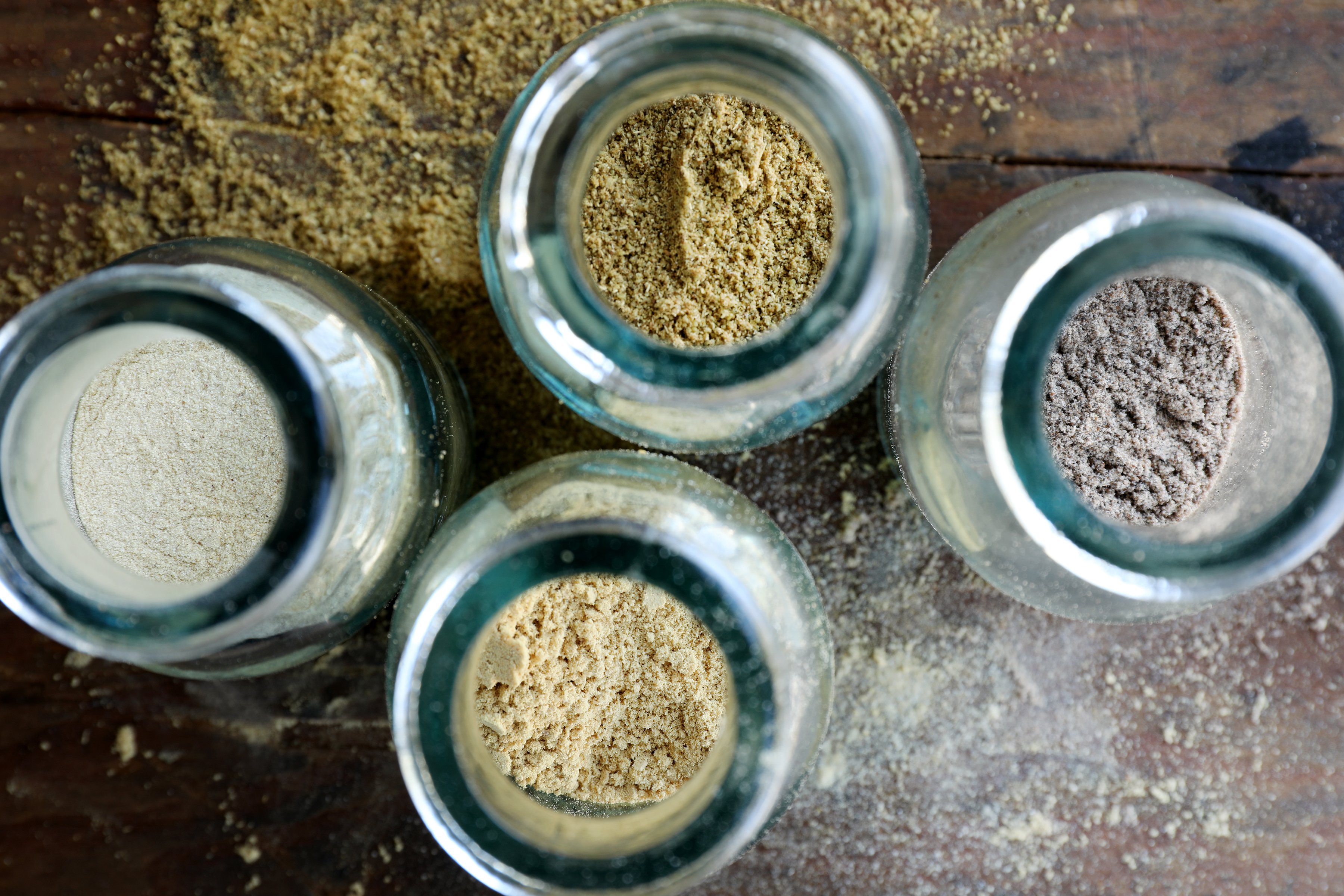 Four spice bottles filled with colorful herbs. 