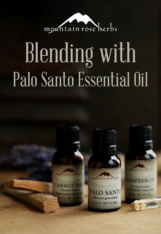 Essential oil bottles arranged with lavender, palo santo sticks, and a dark background. 