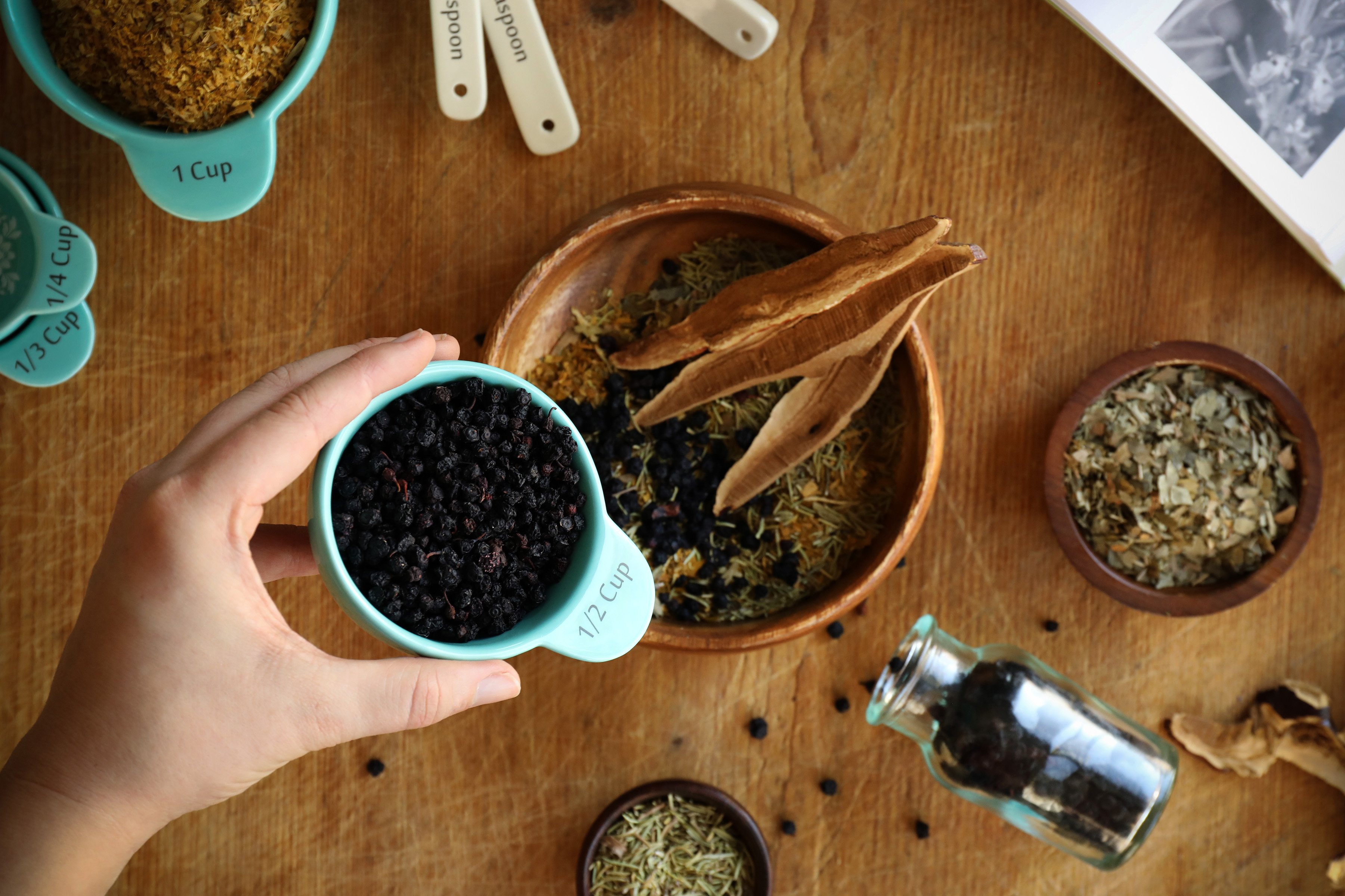 Using a half cup measuring vessel to pour organic dried bilberries into an herbal formula is simple when measuring in parts. 