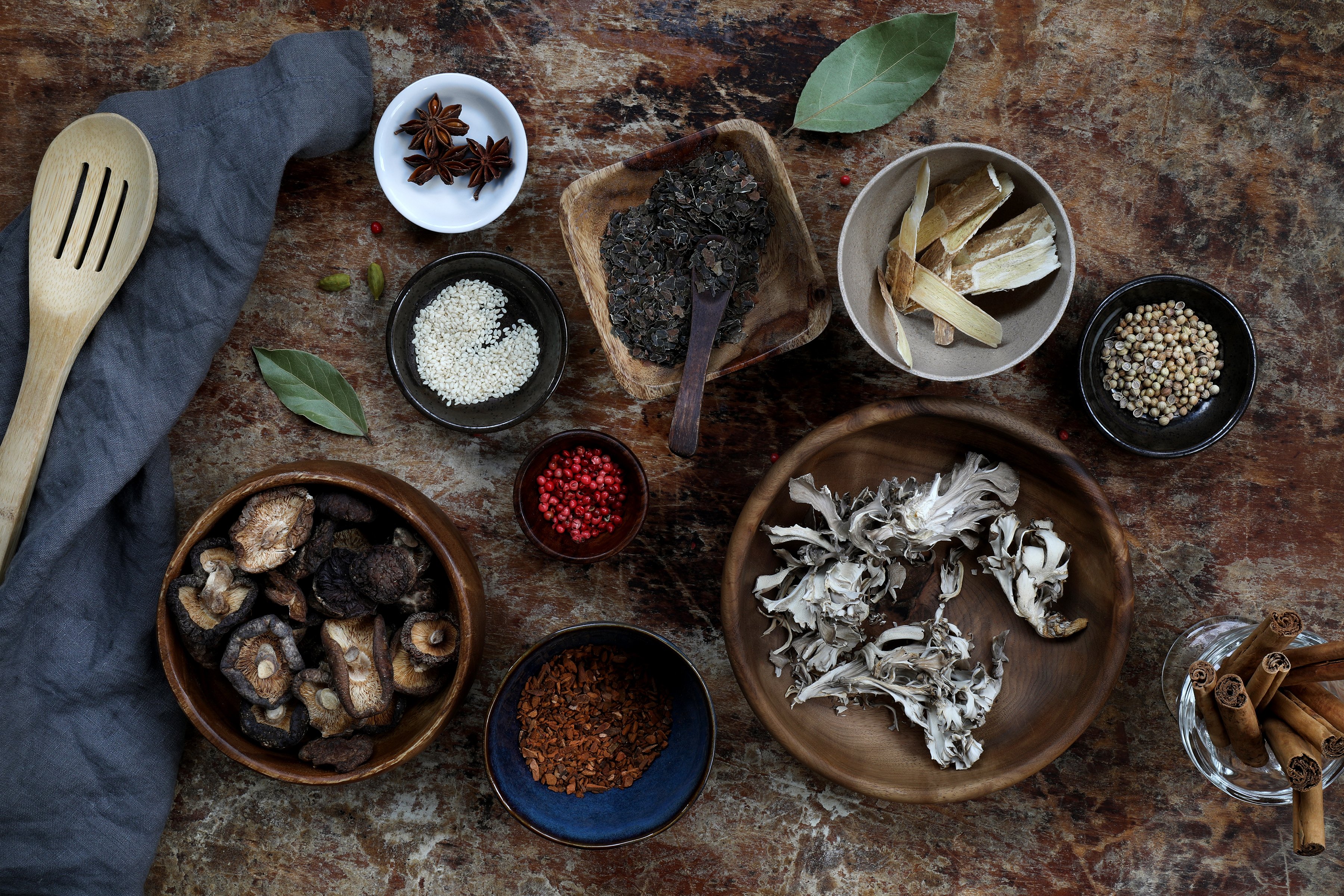 Various sized and shaped bowls filled with colorful mushrooms and spices. 