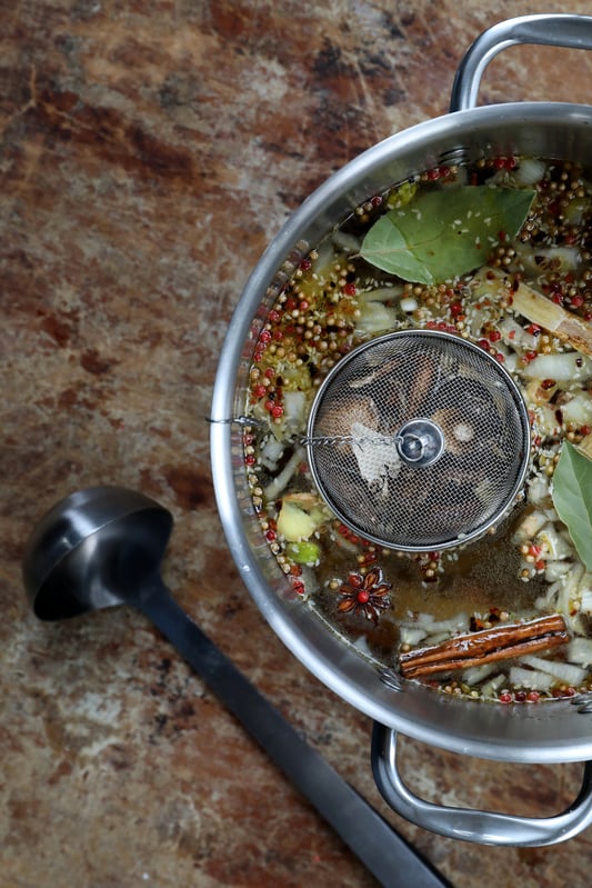 Pot of colorful soup on a marble slab with ladle nearby. 