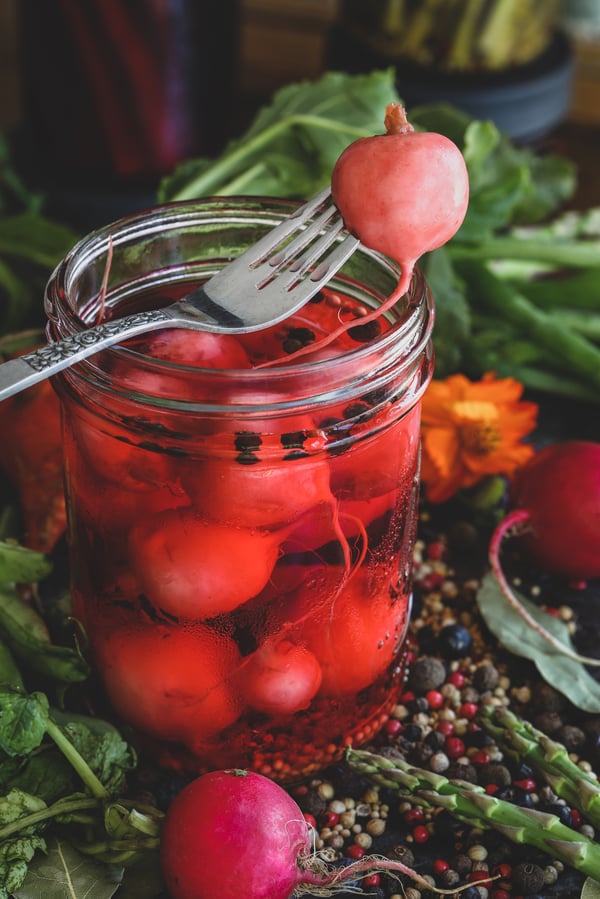 Colorful produce with jar of pickled radishes. 