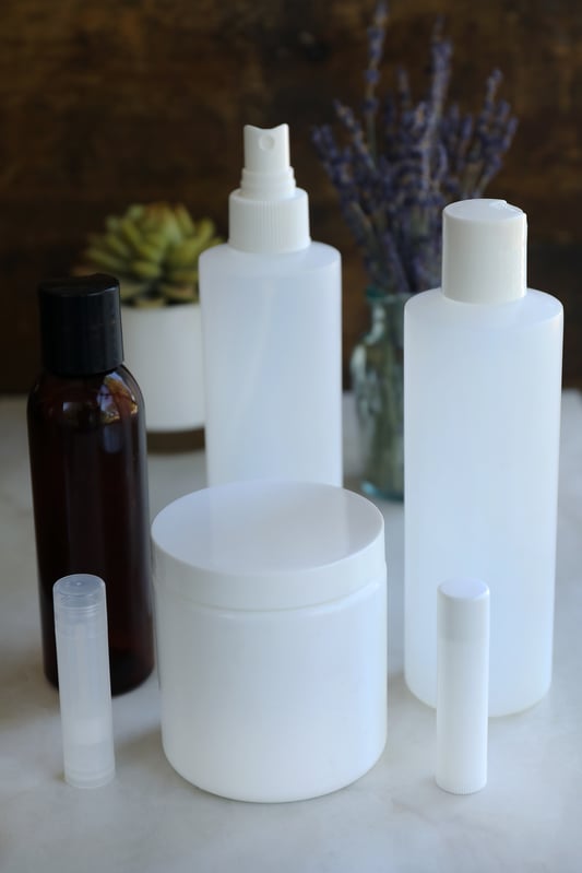 Plastic containers made for lip balm, lotions, oils, sprays, creams, and salves are prepared to be re-purposed. Opaque, clear, and brown plastic bottles to be recycled and reused. 