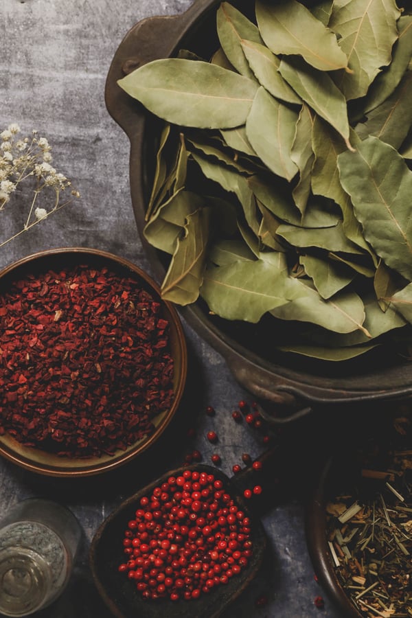 A variety of green and red herbs in bowls in preparation for making potpourri.