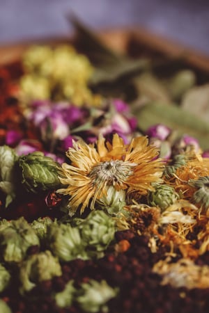 Des herbes séchées mélangées dans un bol pour faire une base de pot-pourri maison.