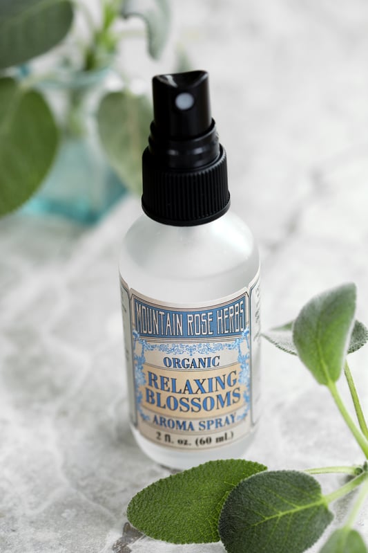 Bottle of Relaxing Blossoms Aroma Spray with fresh sprigs of botanicals. 