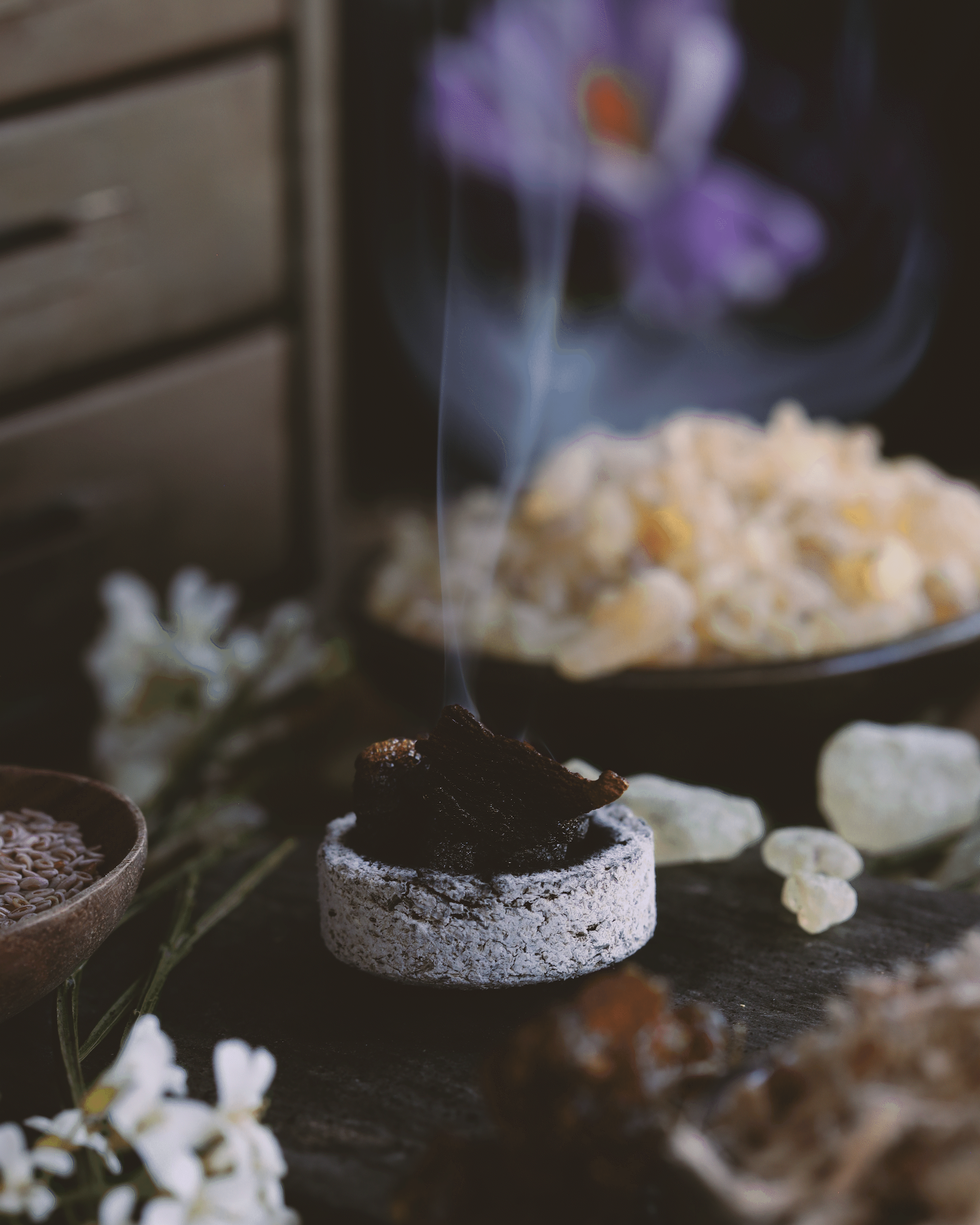 Resin incense burning on a charcoal round with smoke rising.
