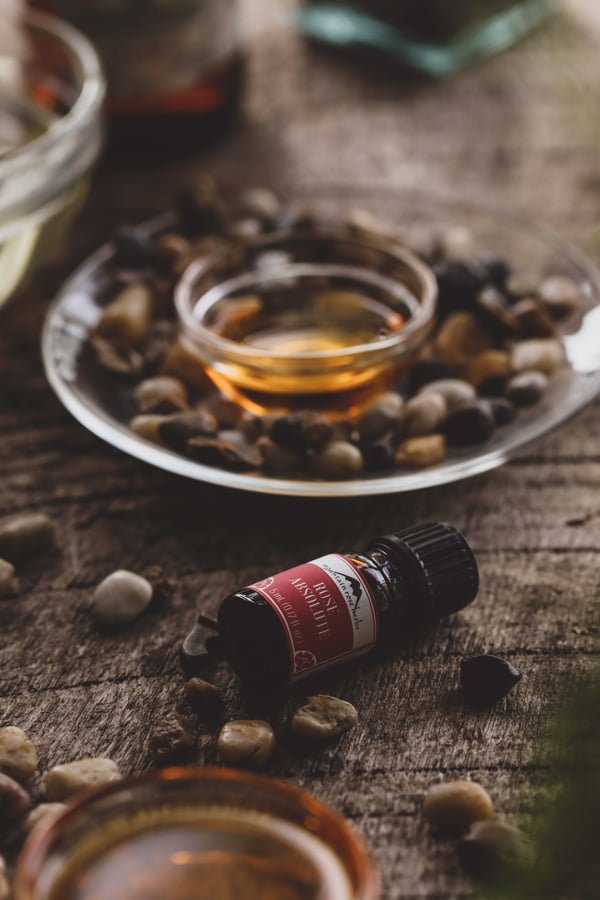 Bottle of rose essential oil in warm setting with small stones