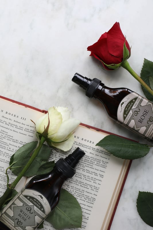 glass bottles of white rose and rose hydrosols laying out near