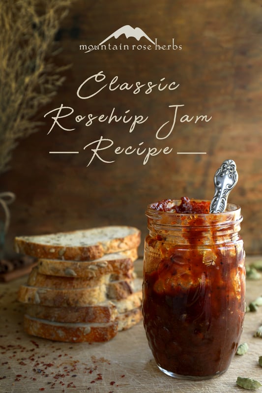 Pinterest link to Mountain Rose Herbs. A jar of homemade rosehip jam using dried rosehips and other ingredients. Toasted whole grain bread and a cheese and fruit board with orange juice in the background.