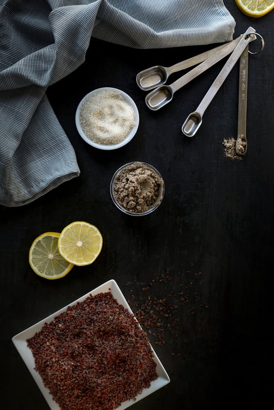 Ingredients for a freezer jam made with dried organic rosehips, fresh lemon, organic cardamom powder, and cane sugar.