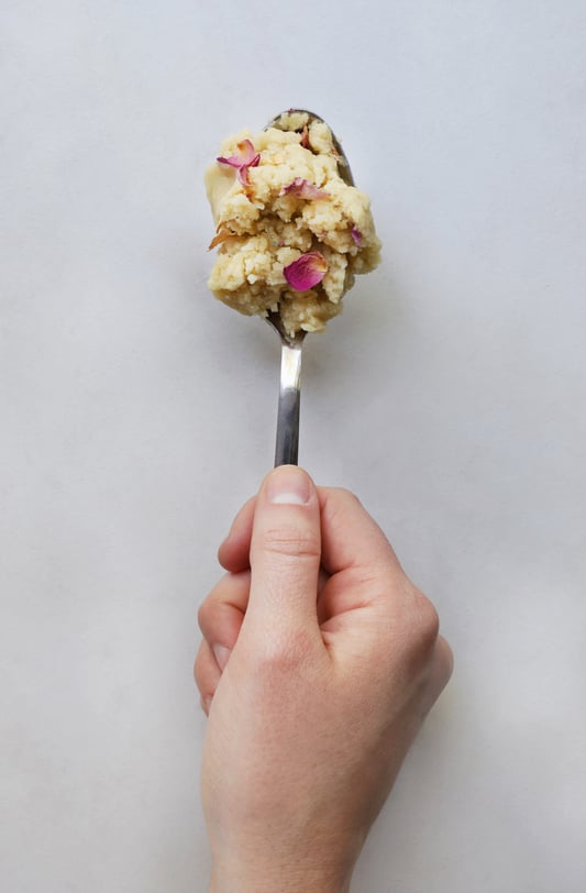 Hand holding spoon filled with rose shortbread dough