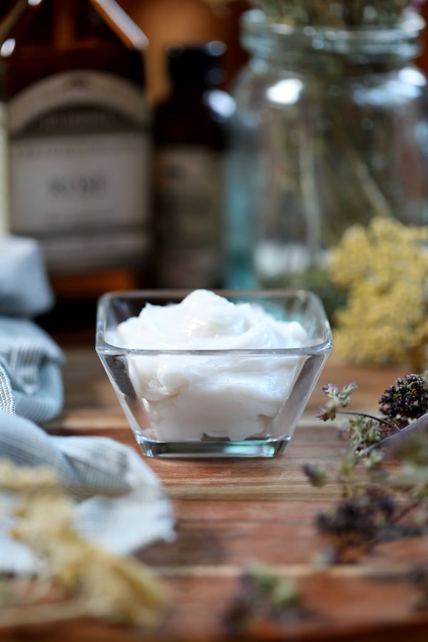 Bowl of Homemade Skin Cream surrounded by dried flowers. 