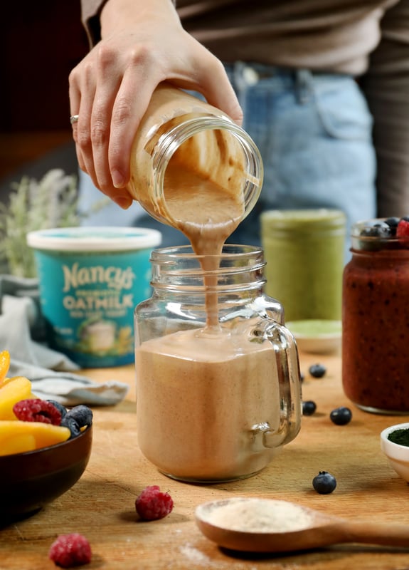 Chocolate, banana, and mushroom smoothie being poured into mason jar glass.