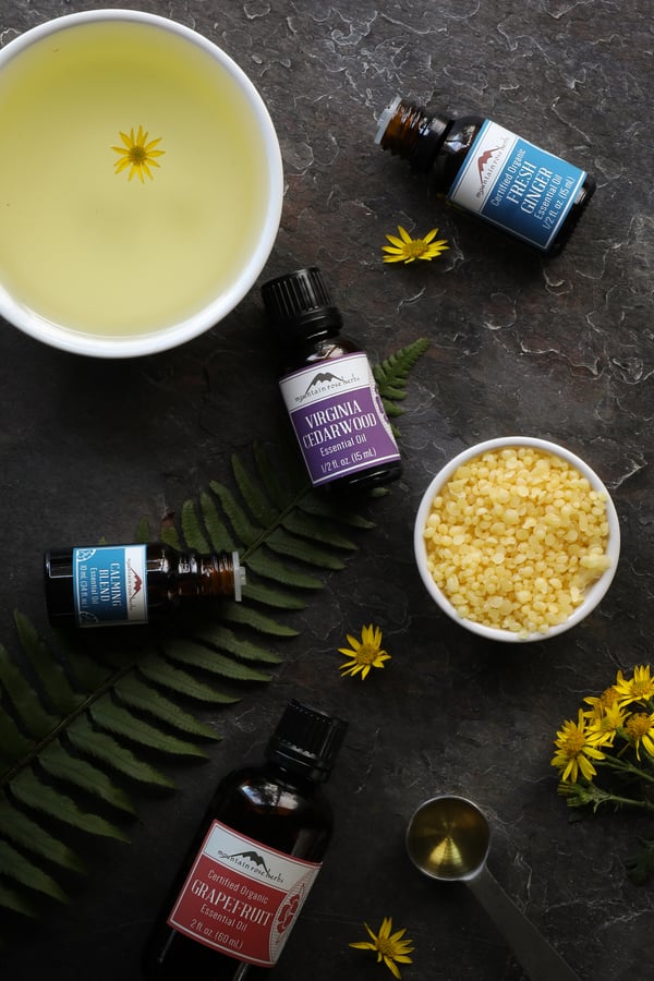 Mountain Rose essential oils on a table with beeswax pastilles and sunflower oil in preparation for making solid perfumes.