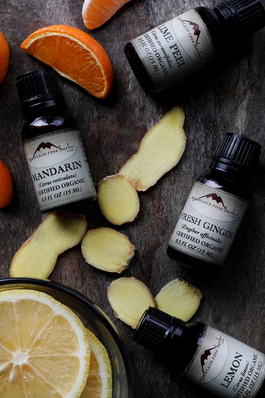 Slices of fresh ginger and fresh mandarins among bottles of essential oils 