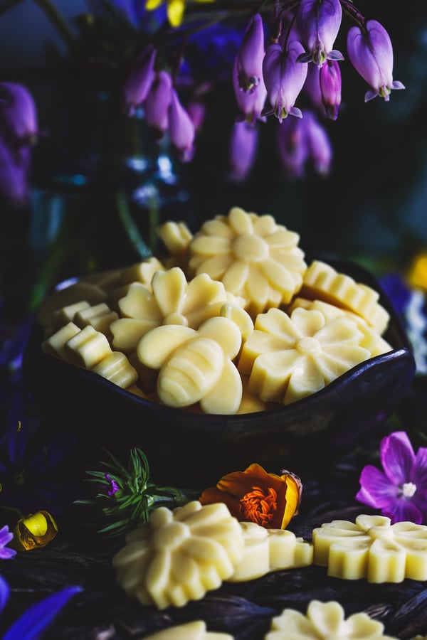 bowl of wax melt in the shapes of bees and flowers and surrounded by bleeding hearts. 