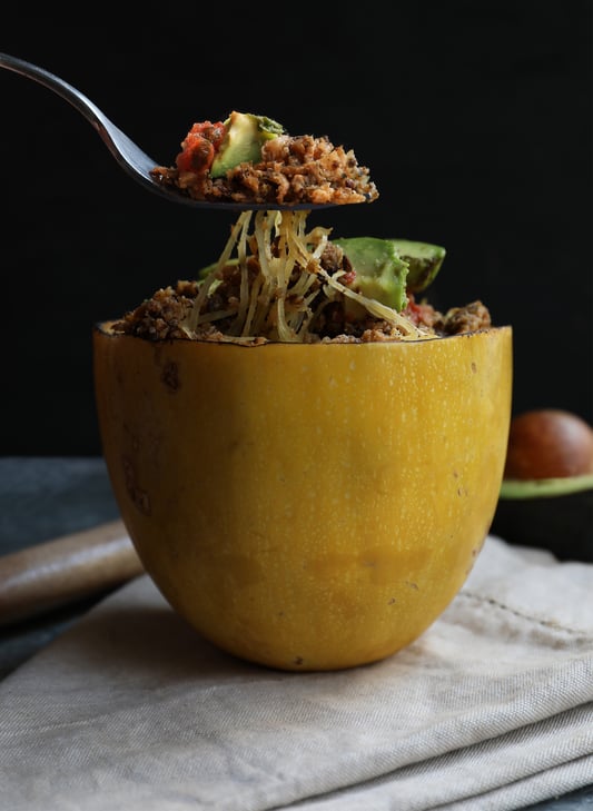 Fork lifting spaghetti squash noodles out of spaghetti squash bowl