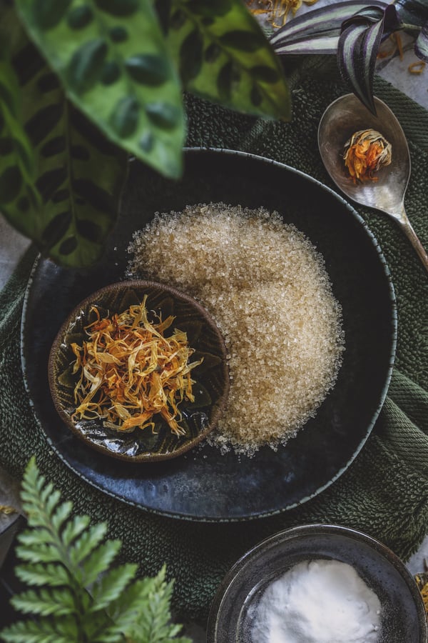 Small bowls with sugar, calendula flower petals, and baking soda. 