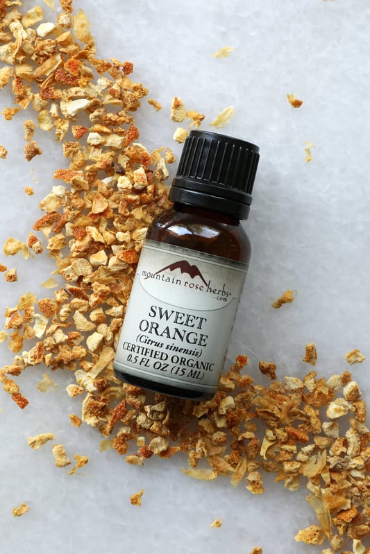 1/2 oz bottle of Mountain Rose Herbs sweet orange essential oil on dried orange peel