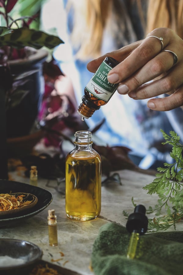 Tea Tree essential oil being dripped into bottle of carrier oil. 