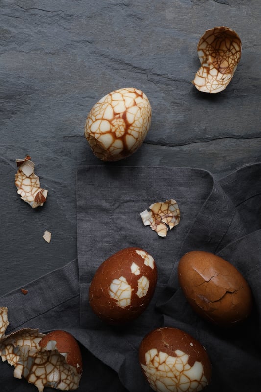 Marbled tea eggs laying out on napkins with shells semi-cracked 