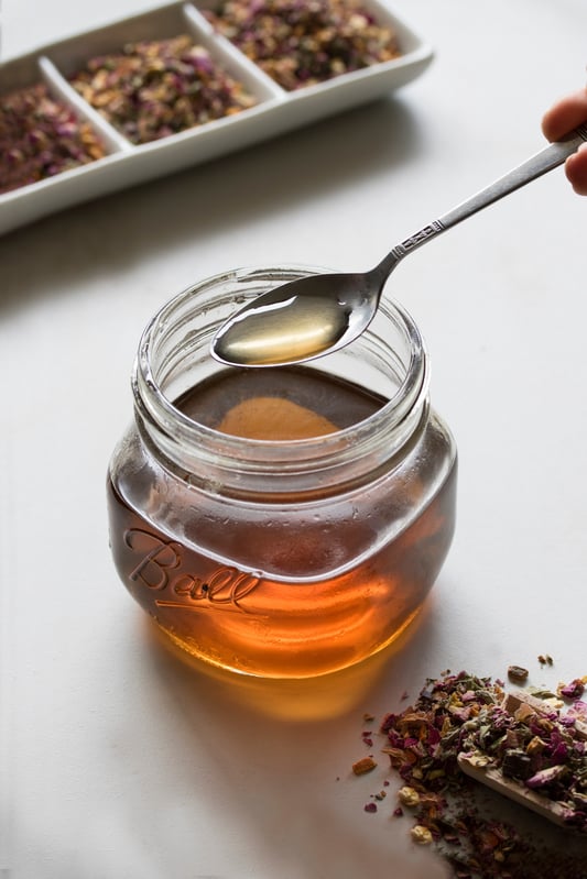 Herbal syrup in a glass mason jar with a spoon and loose leaf tea 