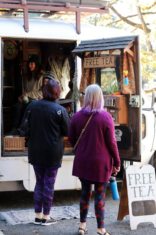 Two women waiting to be served at a mobile free tea station.