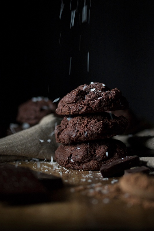 Stack of four chocolate cookies with salt sprinkles on black background