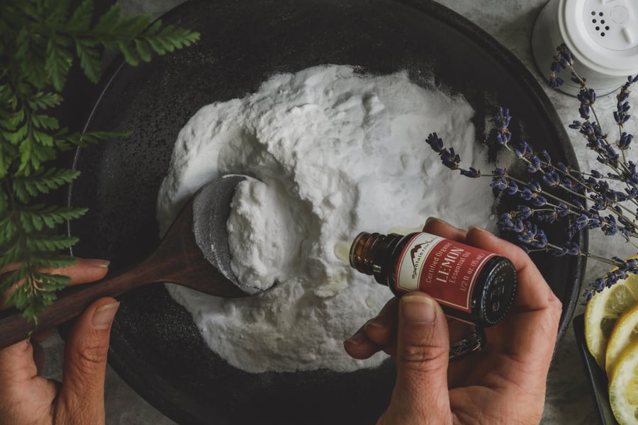 A bowl of DIY cleansing powder with lemon essential oil being added to it.