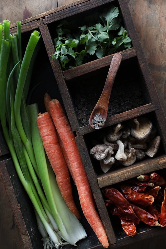 Fresh and dried colorful tom kha soup ingredients in a rustic wooden tray. 