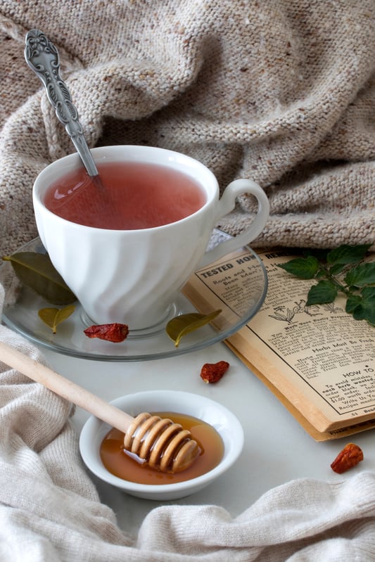 ceramic mug filled with tom kha fire cider next to blanket and honey