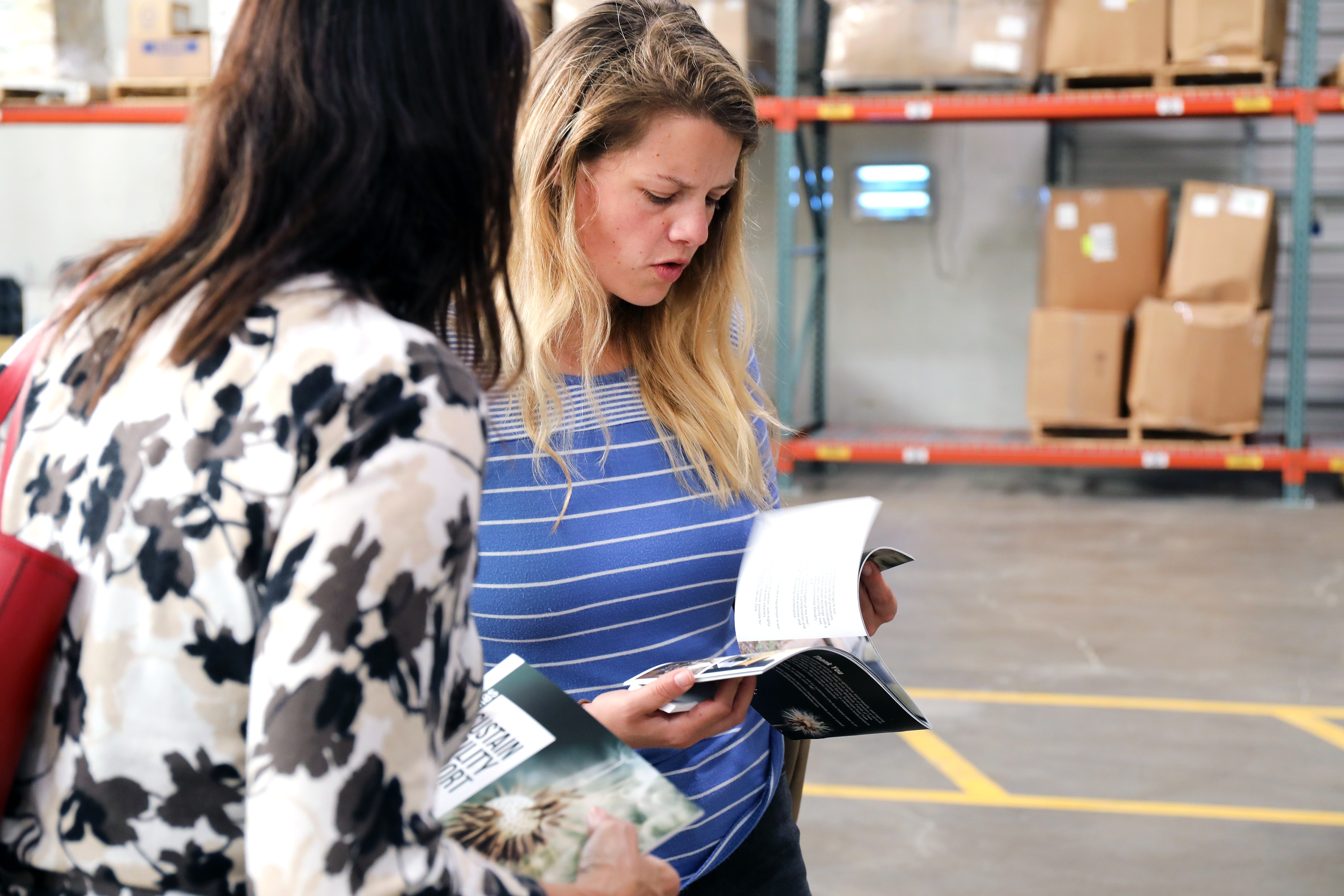Two women reviewing pamphlet in warehouse setting