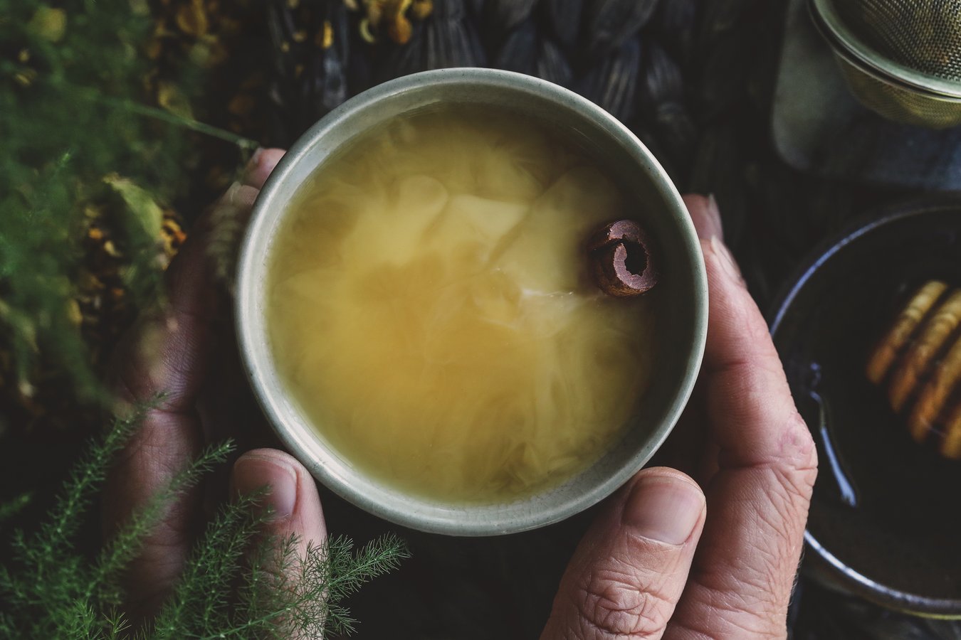 A cup of chai tea is cupped lovingly by two elderly hands.