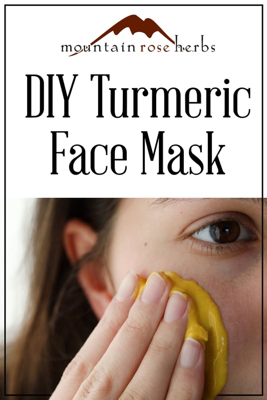 Detail of a woman applying turmeric face mask to the cheeks.