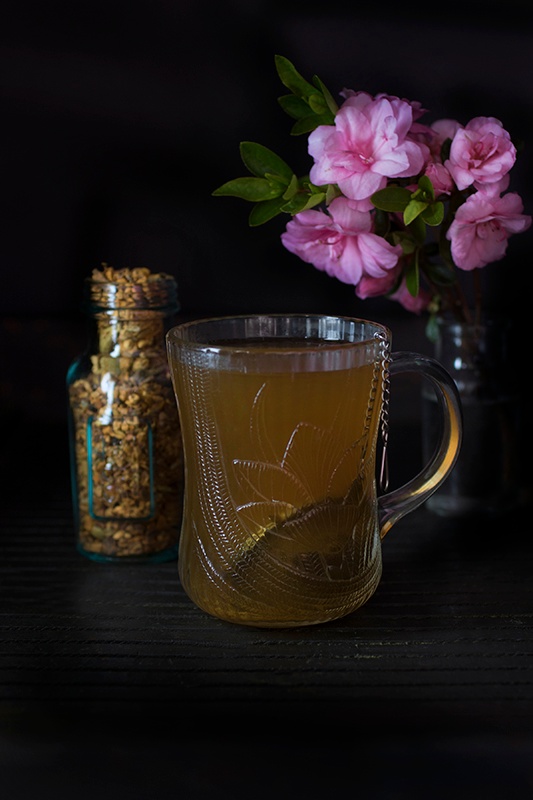 Single glass mug of turmeric chai tea sitting next to bouquet of flowers
