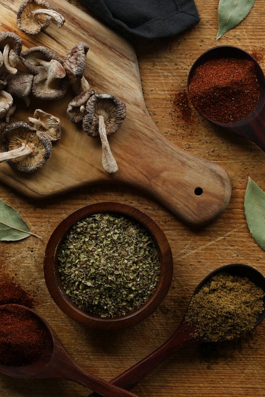 Spices, chili pepper powders, and dried organic shiitake mushrooms are assembled together before being added to the crock pot for a hearty vegan chili. Bay leaves, ancho pepper powder, and cumin seed powder add a depth of flavor and spice. 