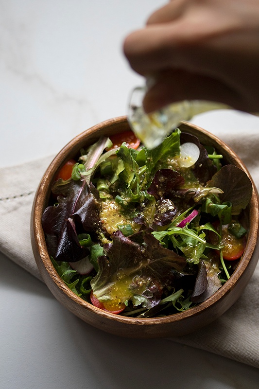 Vinaigrette pouring onto green salad