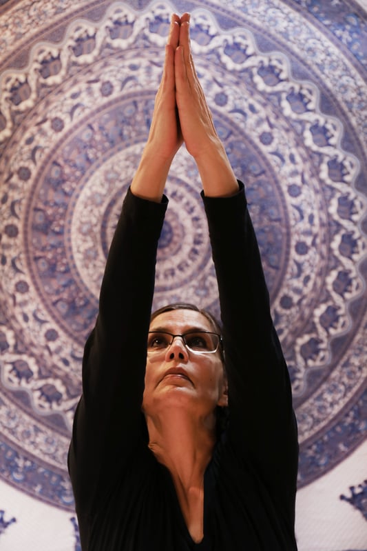 Woman practicing yoga in front of a tapestry