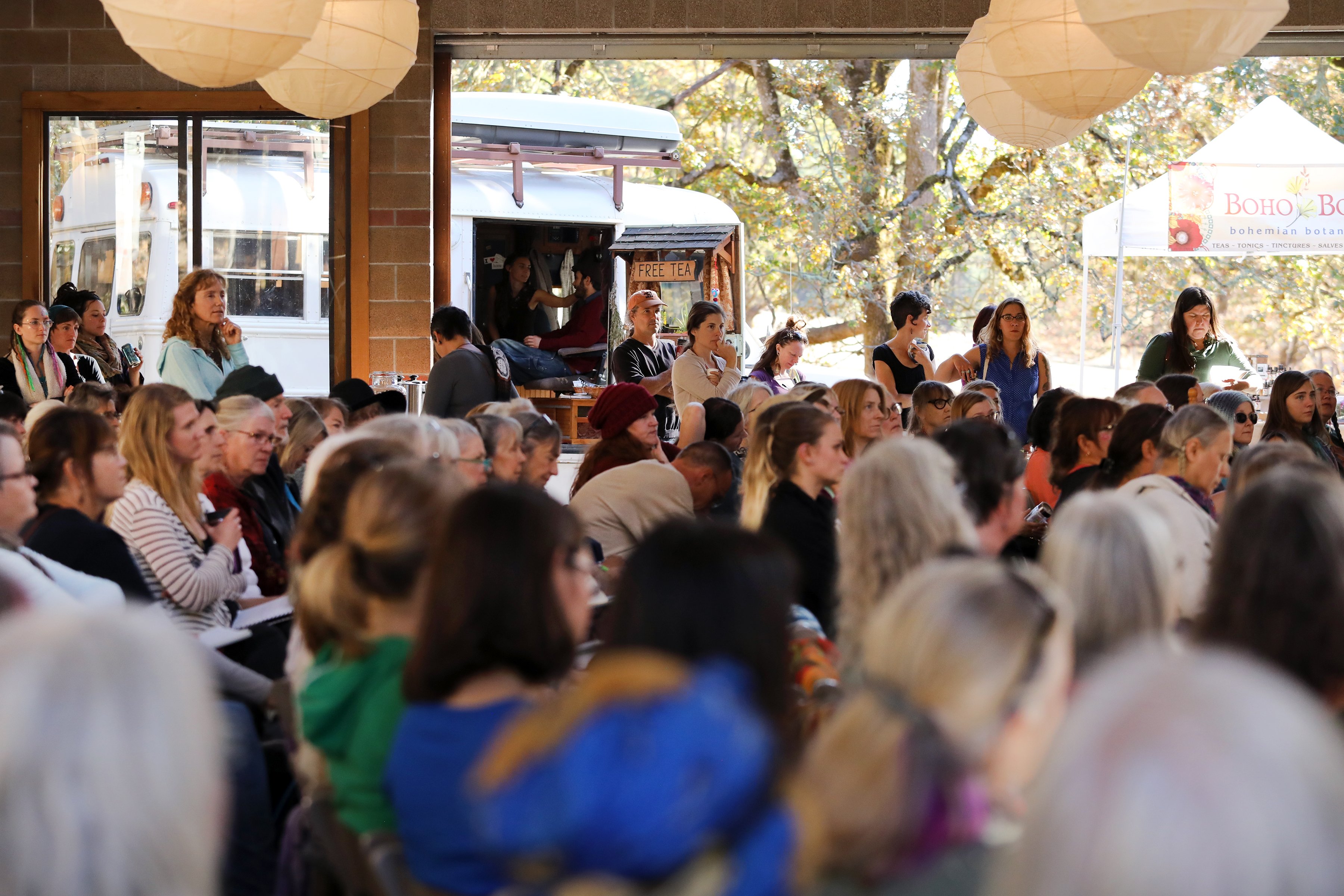 Community members engaging in herbal education at an open air space.