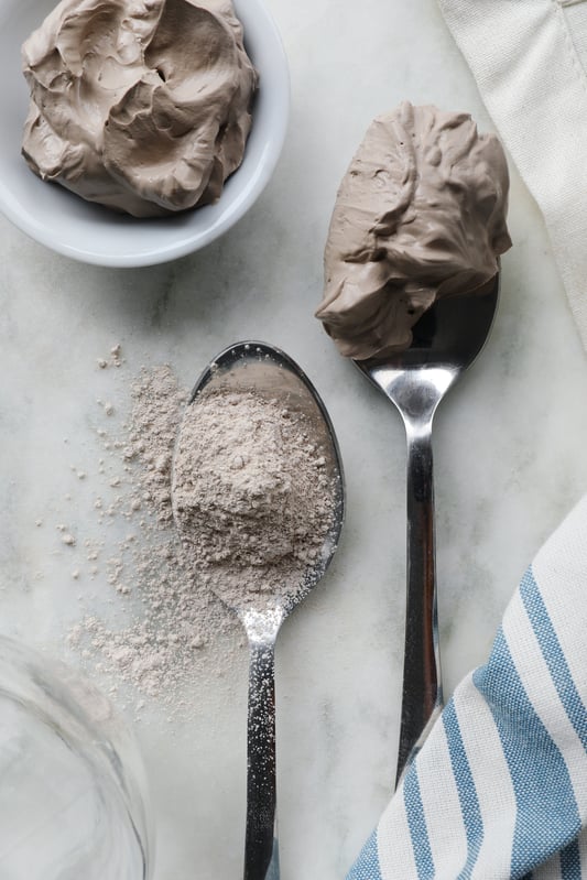 Bowl and spoon with constituted beige clay and a spoon of dried white Kaolin clay spilling off of it. 