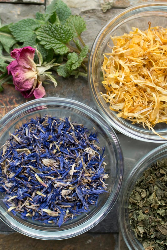 Glass bowls filled with cornflowers and other colorful herbs