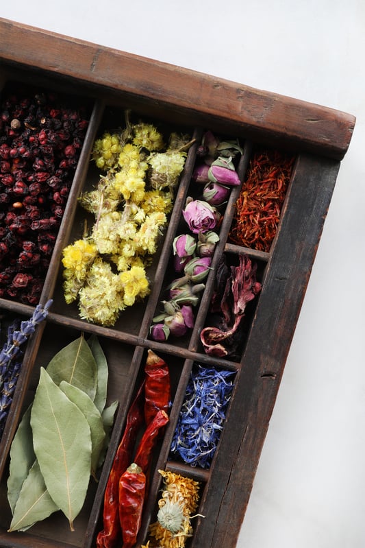 Colorful herbs displayed in rustic wooden box. 