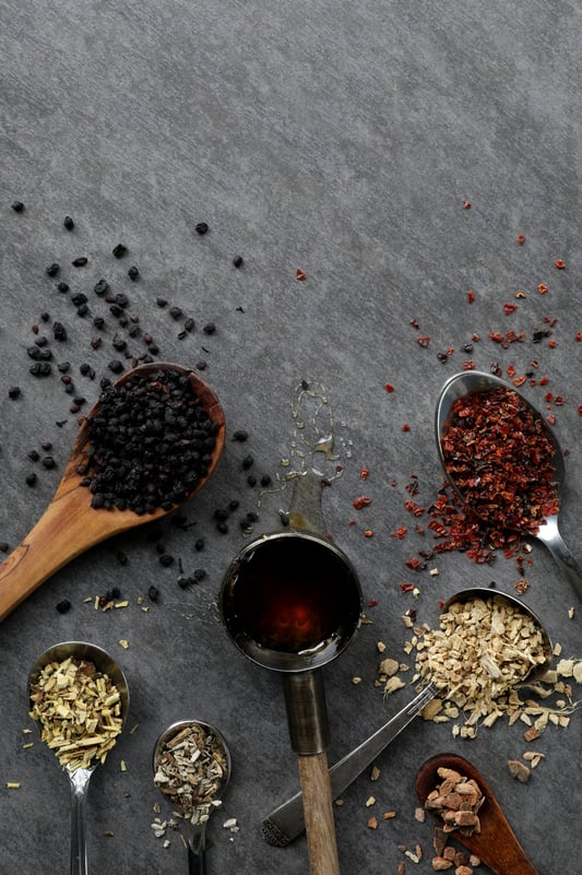 Colorful roots, berries and honey spilling out of spoons. 