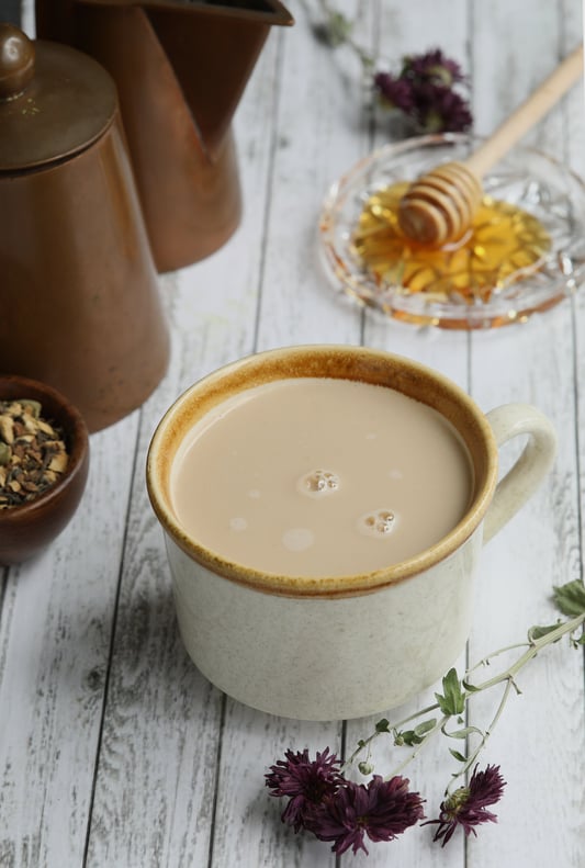 Creamy Maca Latte in mug on wooden table with chai tea and honey